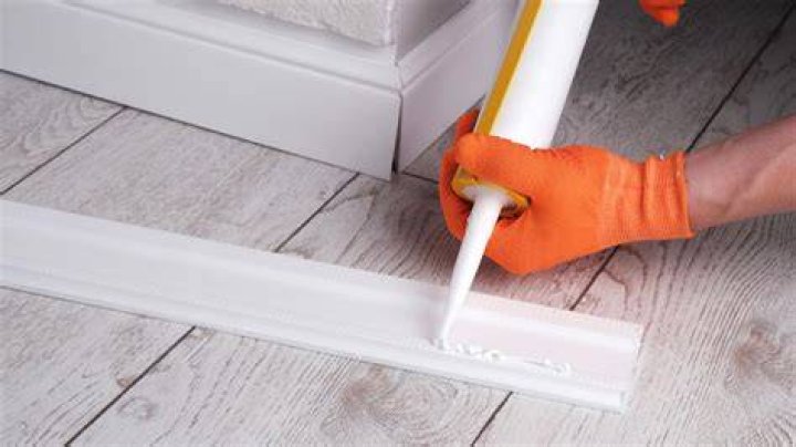 How do you glue baseboard to concrete?