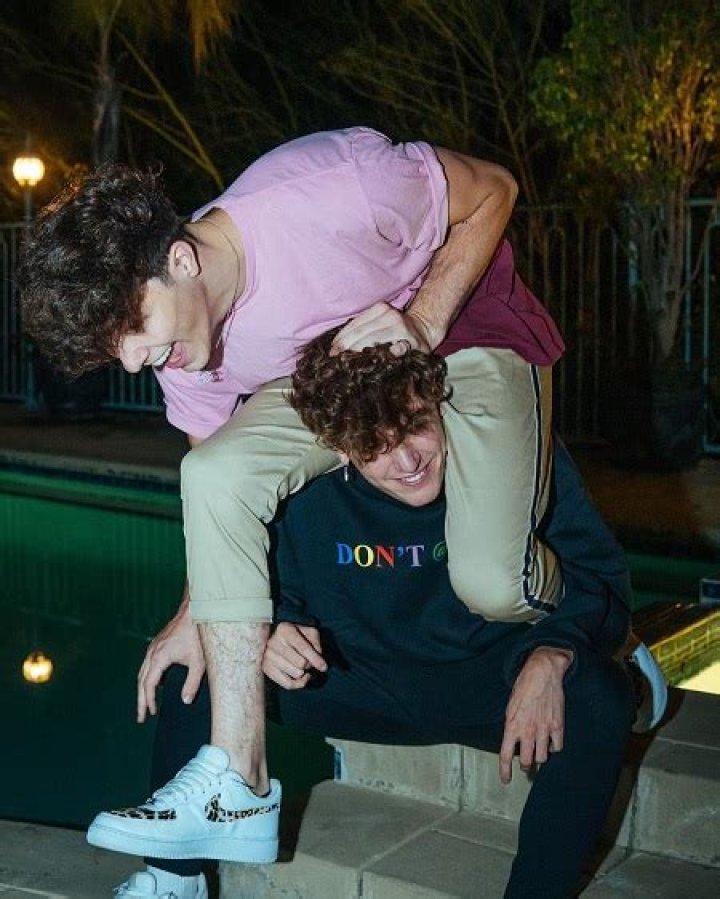 Tayler Holder climbing on Bryce Hall's shoulders who is sitting.